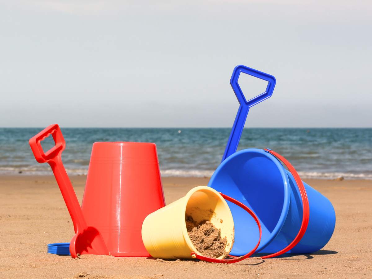 Buckets with sand laying sideways on a beach.