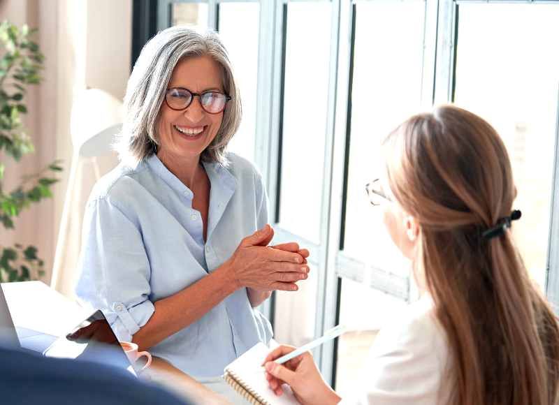 Older woman speaking with younger colleague at work.